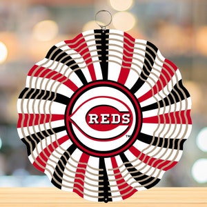 Könnte beinhalten: Ein roter, weißer und schwarzer Windfänger mit dem Logo der Cincinnati Reds und dem Wort "REDS" in weißen Buchstaben. Der Windfänger hat einen gewellten Rand und einen Metallring oben zum Aufhängen.