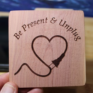 May include: A wooden coaster with the text "Be Present & Unplug" and a heart with a cord plugged into it.