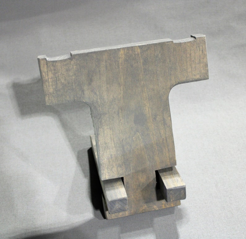 May include: A wooden phone stand with a T-shaped design. The stand is made of dark wood and has a rustic finish.