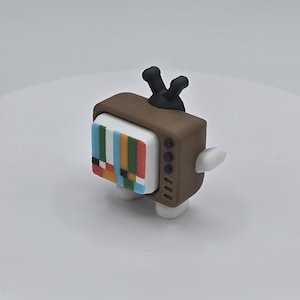 May include: A white ceramic mug with a black handle and the text "But First, Coffee" in a bold, black font. The mug is filled with a dark liquid, likely coffee, and sits on a light-colored surface.