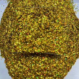 May include: A close-up of a pile of gold glitter with iridescent shimmer. The glitter is in a heart shape and has a variety of sizes.