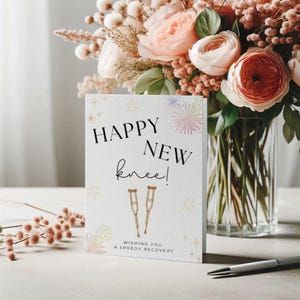 May include: A get-well card with the text "Happy New Knee!" and "Wishing You a Speedy Recovery" is displayed. The card features illustrations of crutches and decorative fireworks. A bouquet of pink and peach flowers is in the background.