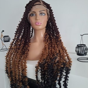 Puede incluir: Una cabeza de maniquí muestra una peluca larga y rizada con una parte delantera de encaje. La peluca presenta un degradado de colores, comenzando con marrón oscuro en las raíces, pasando a un marrón dorado y terminando con puntas negras. Los rizos son apretados.