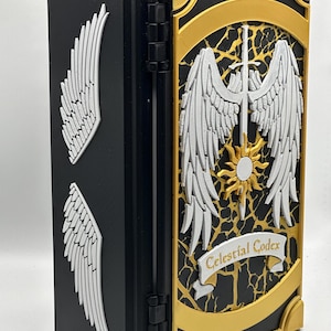 May include: A black book with white wing designs on the side and front. The front cover features a gold border, white wings, a sword, and the text "Celestial Codex" on a banner. The book is open, revealing the interior.