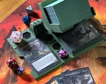 May include: A green card holder with multiple compartments, holding a large stack of cards. Several multi-sided dice in various colors are scattered around the holder. The cards feature illustrations and text, suggesting a collectible card game.