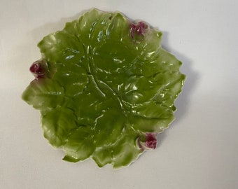 May include: A green ceramic dish shaped like a leaf with three pink flower buds.