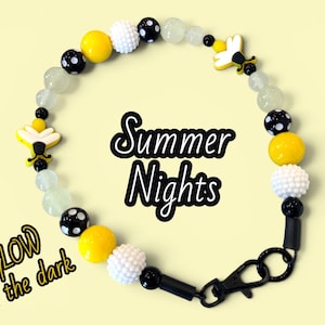 May include: A beaded bracelet featuring yellow, white, and black beads, including polka-dot patterns and bee-shaped charms. The bracelet includes translucent beads and a black lobster clasp. Text on the image reads Summer Nights and GLOW in the dark.