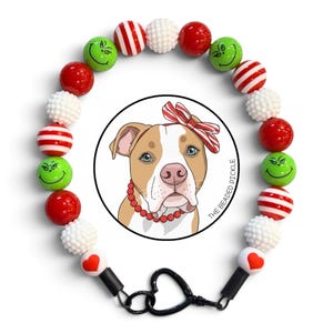 May include: A circular beaded necklace featuring red, white, and green spherical beads, including striped patterns, textured white beads, and green beads with smiling faces. A central circular graphic shows a dog with a red and white striped bow.