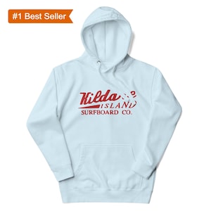 May include: A light blue hooded sweatshirt with a kangaroo pocket and a drawstring hood. The front features the red text "Hilda Island Surfboard Co." in a vintage style. A "#1 Best Seller" tag is in the upper left corner.