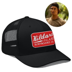 May include: A black trucker hat featuring a rectangular red patch on the front with white embroidered text that reads Kildare Island Surfboard Co. The cap has a solid front panel and a breathable mesh back panel with a curved brim.