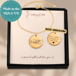 Pode incluir: Pulseira dourada com um pendente redondo com um design de tubarão-martelo. A pulseira é apresentada numa caixa preta. O texto inclui "Back Engraving" e "Your custom message on the back". A frase "a special gift just for you" também é visível.