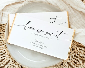 May include: White chocolate bar wrapper with gold foil accents. The wrapper has black calligraphy that reads "love is sweet" and "Please take a treat". Below the text is "Thank you" and the names "Sophia + Andrew" and the date "17.06.2023".