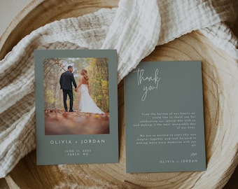 May include: A thank you card featuring a photograph of a couple in a woodland setting. The card is light blue with white text that reads "Thank you!" and "From the bottom of our hearts we would like to thank you for celebrating our special day with us and making it the most memorable day of our lives. We are so excited to start this new chapter together and look forward to making many more memories with you all. Olivia + Jordan".