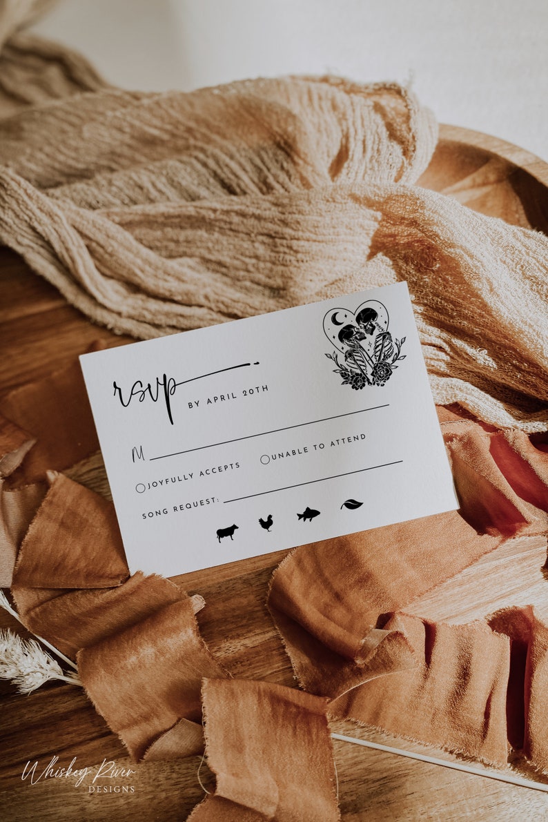 May include: A white RSVP card with black text and a black and white illustration of two skeletons holding hands. The text reads "RSVP by April 20th". There are two radio buttons for guests to select: "Joyfully Accepts" and "Unable to Attend". There is a space for a song request and a row of icons for guests to choose from.