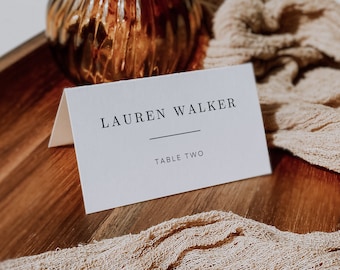 Può includere: Segnaposto bianco con testo nero che recita "LAUREN WALKER" con una linea sottostante e "TABLE TWO" sotto la linea.