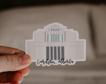 May include: White sticker with a simple illustration of a church building and the text "Cardston, Alberta".