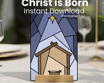 May include: A Christmas-themed printable file with the text "Christ is Born Instant Download Printable File." The image features a stained-glass style illustration of a nativity scene with a star above the stable.