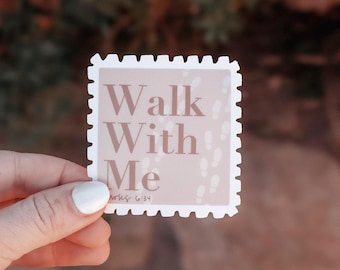 May include: A square sticker with a light pink background and the words "Walk With Me" in a soft brown font. The sticker has a white border with a postage stamp edge. Small footprints are printed on the background.