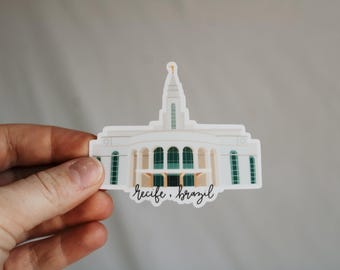 May include: White sticker of a church building with green windows and a spire. The text "Recife, Brazil" is written below the building.