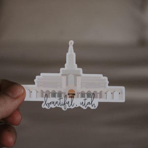 Op de afbeelding: Een witte sticker met een silhouet van een tempel en de tekst "beautiful. utah" in zwarte schrijfletters.