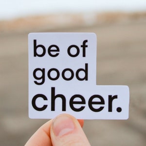 May include: White sticker with black text that reads "be of good cheer."