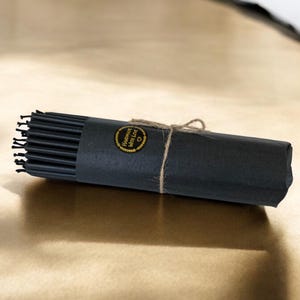 May include: A roll of black hair ties wrapped in black paper with a gold label that says "Handmade with Love".