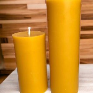 May include: Two yellow beeswax candles of different sizes. The larger candle is about 8 inches tall and the smaller candle is about 4 inches tall.