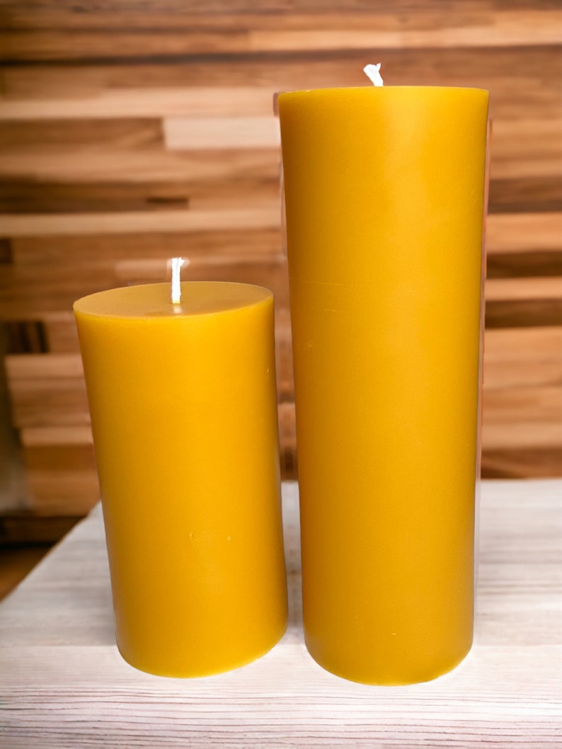 May include: Two yellow beeswax candles of different sizes. The larger candle is about 8 inches tall and the smaller candle is about 4 inches tall.