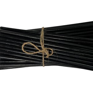 May include: A bundle of black taper candles tied together with twine.