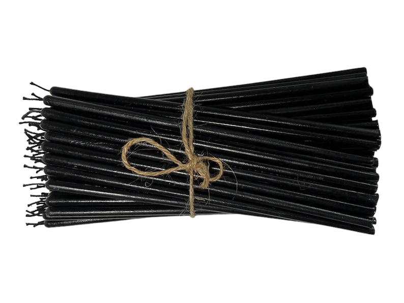 May include: A bundle of black taper candles tied together with twine.