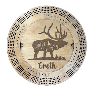 May include: A wooden cribbage board with a laser-engraved elk design and the name "Groth". The board has a circular shape with a numbered track around the edge.
