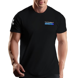 May include: A black short-sleeved t-shirt featuring a small graphic on the left chest area. The graphic displays the white text "I'm Friendly :)" above a blue rectangular bar containing the white text "Enko Pistol 3s". A white logo is on the sleeve.