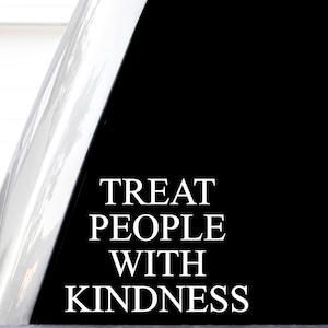 May include: A black decal featuring the white text TREAT PEOPLE WITH KINDNESS in a serif font. The sticker is applied to a smooth, reflective surface, showing a clean, high-contrast design with bold, legible lettering centered on the dark background.