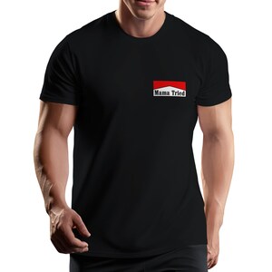 May include: A black short-sleeved t-shirt featuring a rectangular graphic on the left chest. The graphic consists of a red top section, a white bottom section, and the black text "Mama Tried" printed in a serif font within the white area.