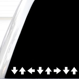 May include: A black decal featuring a horizontal row of eight white directional arrows. The sequence of arrows points in the following directions: down, up, left, down, up, right, down, and up. The design is presented on a clear backing sheet.