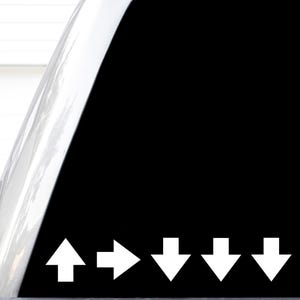 May include: A black decal featuring a sequence of five white arrows. The first arrow points upward, the second points to the right, and the remaining three arrows point downward. The design is presented on a smooth, solid black background.