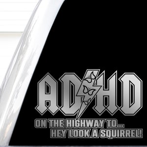May include: Silver vinyl sticker with the text "ADHD On the Highway to... Hey Look a Squirrel!" in a bold, stylized font. The text is on a black background.