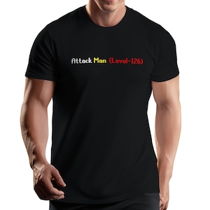 May include: Black t-shirt with the text "Attack Man (Level-126)" in white, yellow, and red pixelated font. The shirt is a crew neck style.