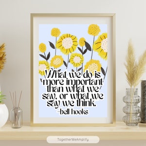 May include: A printable wall art design with a light blue background and yellow flowers. The quote "What we do is more important than what we say, or what we say we think. -bell hooks" is printed in black text.