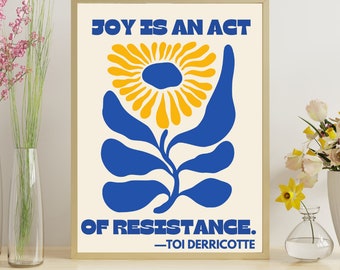 May include: A beige poster with a blue and yellow stylized flower and the text "JOY IS AN ACT OF RESISTANCE. -TOI DERRIOTTE"