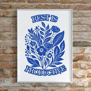 May include: A white framed print with a blue floral design and the text "REST IS PRODUCTIVE".