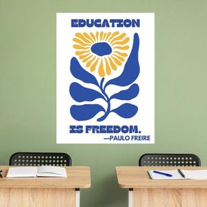Pu&ograve; includere: Un poster bianco con illustrazioni blu e gialle di un fiore. Il poster recita "EDUCATION IS FREEDOM. -PAULO FREIRE".