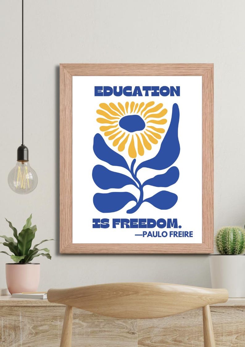 Pu&ograve; includere: Una stampa incorniciata con un design floreale blu e giallo. Il testo "EDUCATION IS FREEDOM." &egrave; stampato sotto il fiore. La citazione &egrave; attribuita a "PAULO FREIRE".
