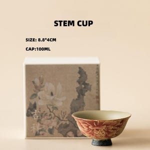 May include: A stem cup with a floral design, 3.5 inches wide and 1.6 inches tall, with a capacity of 3.4 fluid ounces. The cup has a red and gold floral pattern and a black base. The box behind the cup has a floral design and the words "STEM CUP".