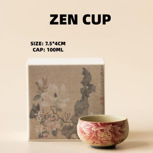 May include: A small, round ceramic Zen cup with a floral design in shades of red and pink. The cup is displayed in front of a box with floral artwork. The text "ZEN CUP" and size information are visible.