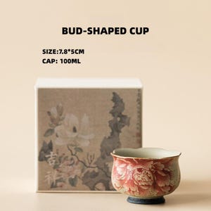 May include: A bud-shaped cup with a floral design, accompanied by a box with a floral illustration. The cup is approximately 3 inches wide and 2 inches tall, with a capacity of 100ml. The text "BUD-SHAPED CUP" is displayed above the cup.