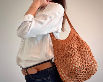 Puede incluir: Un bolso tote de ganchillo en color naranja quemado con un patrón de malla de rombos calados y un borde superior sólido y tejido apretado con una sola correa para el hombro. El bolso está hecho de hilo y tiene una estructura flexible.