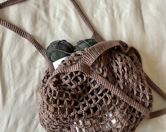 May include: A brown crocheted string bag with two balls of dark green yarn inside.