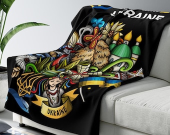 May include: Black fleece throw blanket with a colorful illustration of Ukrainian cultural symbols, including a woman in traditional clothing, a sunflower, and the words "UKRAINE" and "UKRAINE".