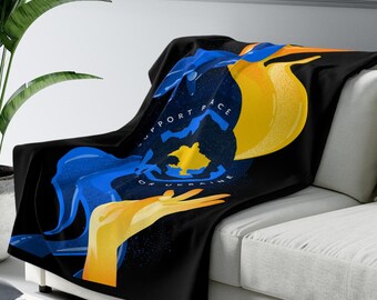 May include: A black fleece throw blanket with a blue and yellow design. The design features a stylized image of a hand holding a globe with the text "Support Peace of Ukraine".